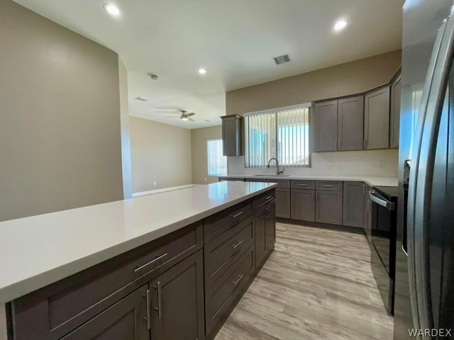 kitchen with range with electric stovetop, light countertops, visible vents, a sink, and stainless steel fridge with ice dispenser