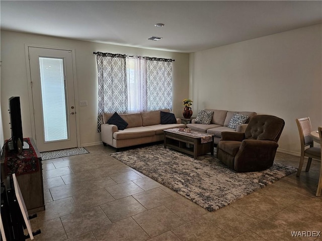 living area with tile patterned flooring, visible vents, and baseboards