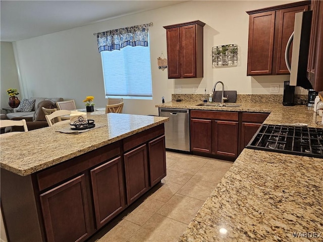 kitchen with light stone countertops, appliances with stainless steel finishes, a kitchen breakfast bar, and a sink