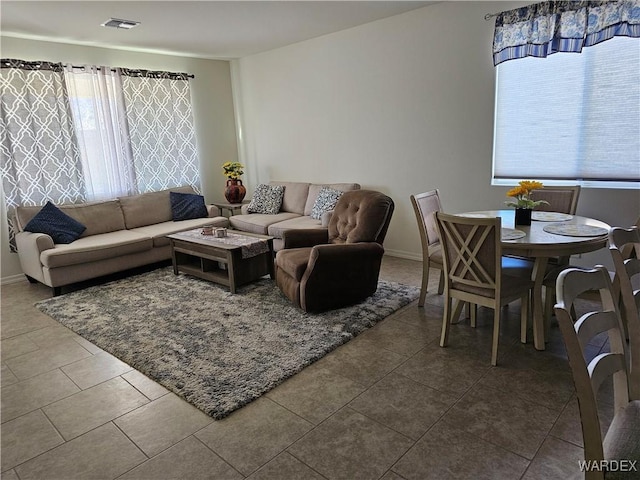 tiled living area featuring a wealth of natural light, visible vents, and baseboards