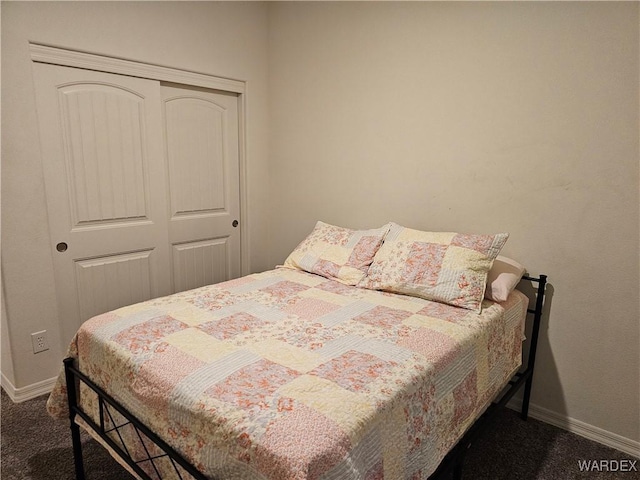 bedroom featuring baseboards, dark carpet, and a closet