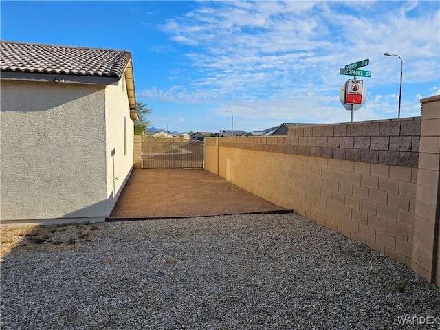 view of yard featuring a patio, fence, and a gate