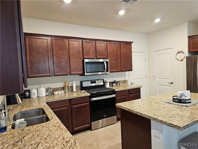 kitchen featuring stainless steel appliances, visible vents, a sink, and light stone countertops