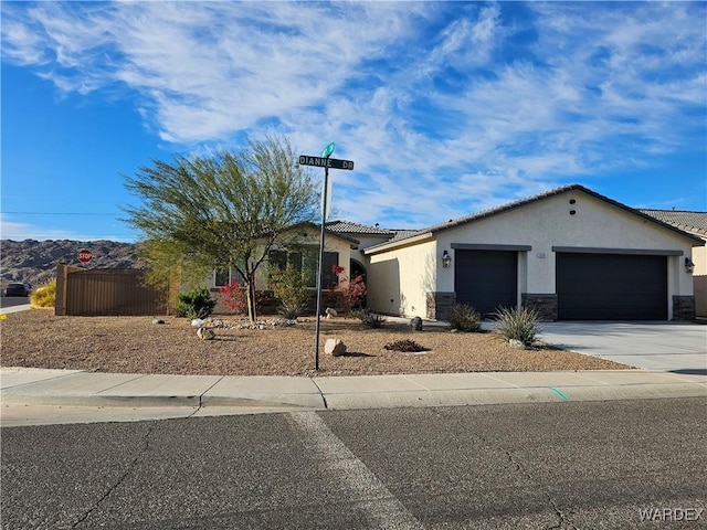 view of front facade with a garage, concrete driveway, stone siding, a tile roof, and stucco siding