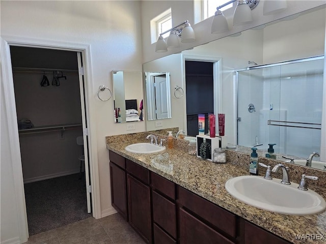 full bath with a sink, double vanity, a stall shower, and a walk in closet