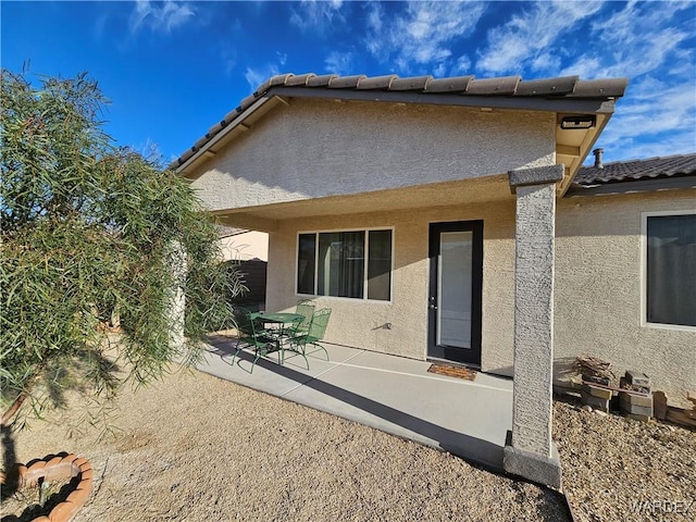 back of house featuring a patio area, a tiled roof, and stucco siding