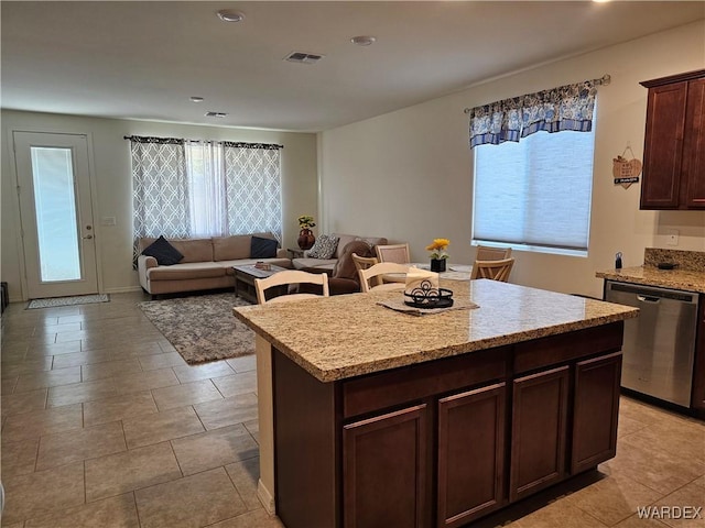 kitchen with light stone counters, visible vents, open floor plan, stainless steel dishwasher, and a center island