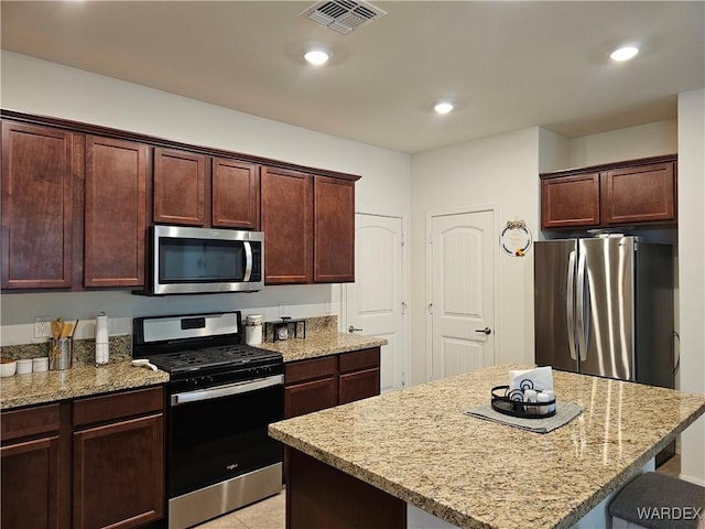 kitchen featuring visible vents, appliances with stainless steel finishes, a center island, light stone countertops, and recessed lighting