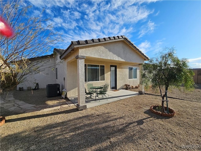 rear view of property featuring central air condition unit, a patio area, a tiled roof, and stucco siding