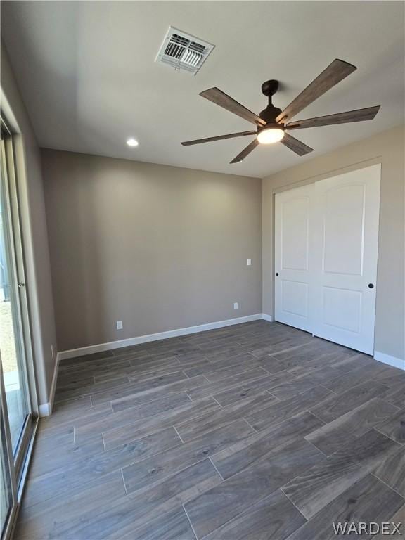 unfurnished bedroom with baseboards, visible vents, ceiling fan, dark wood-style flooring, and a closet