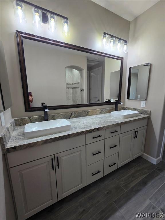 bathroom with double vanity, baseboards, and a sink