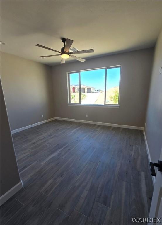 empty room featuring dark wood-style floors, ceiling fan, and baseboards