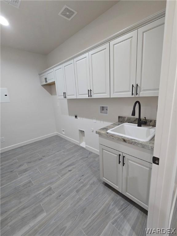 washroom with hookup for a washing machine, hookup for an electric dryer, a sink, visible vents, and cabinet space