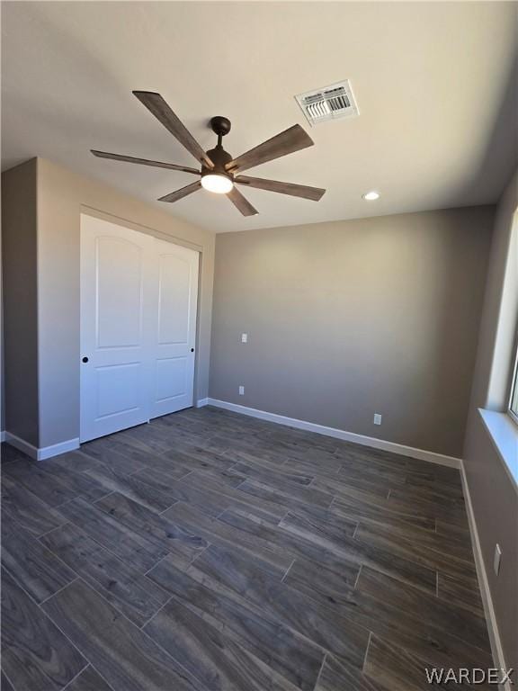 unfurnished bedroom with dark wood-style floors, visible vents, and baseboards