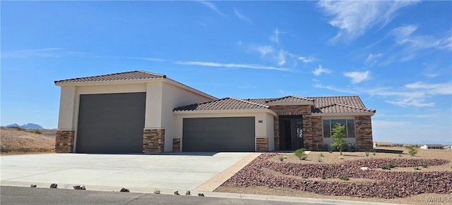 view of front of property with concrete driveway, stone siding, a tiled roof, an attached garage, and stucco siding