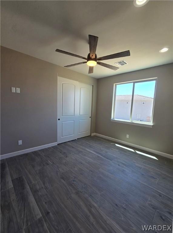 unfurnished bedroom featuring a ceiling fan, baseboards, visible vents, and dark wood-style flooring