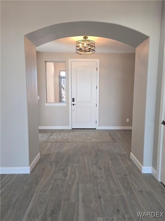 entrance foyer with arched walkways, wood finish floors, and baseboards