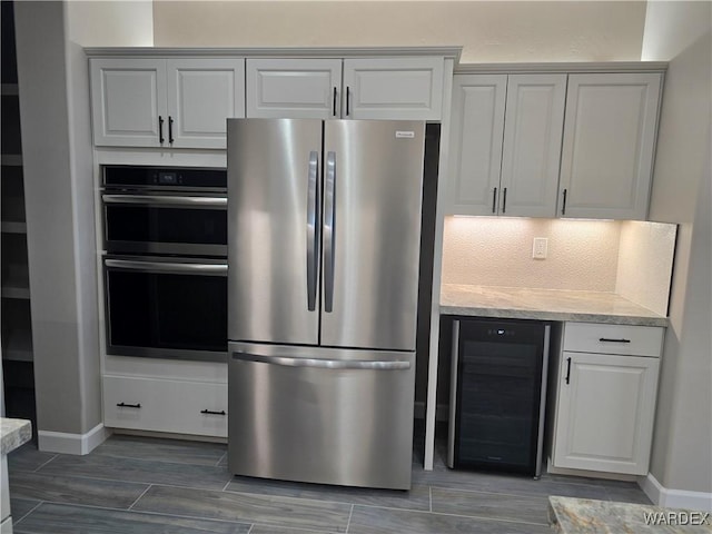 kitchen with baseboards, decorative backsplash, wine cooler, stainless steel appliances, and white cabinetry