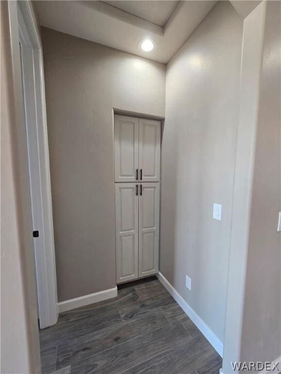 hall featuring baseboards, dark wood finished floors, and recessed lighting