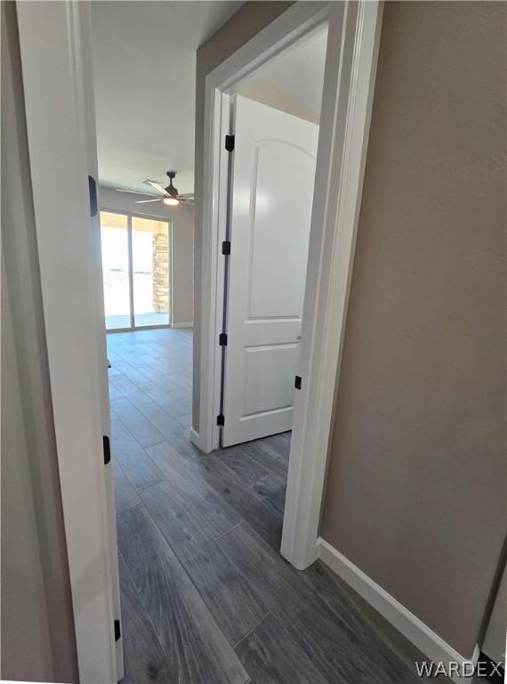 hallway with dark wood-style flooring and baseboards