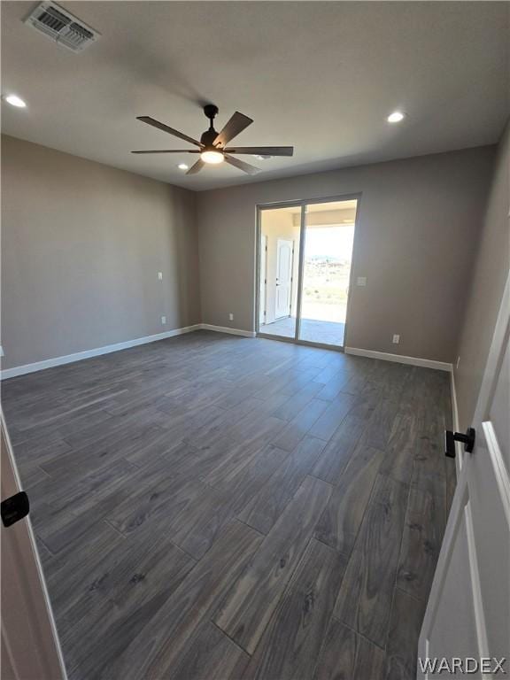 spare room with dark wood-style floors, baseboards, visible vents, and a ceiling fan