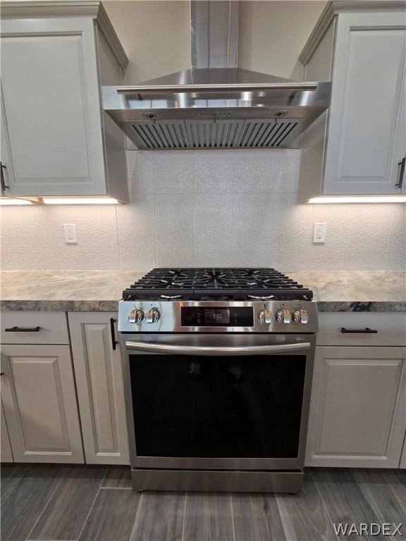 kitchen with tasteful backsplash, stainless steel range with gas cooktop, light countertops, and ventilation hood