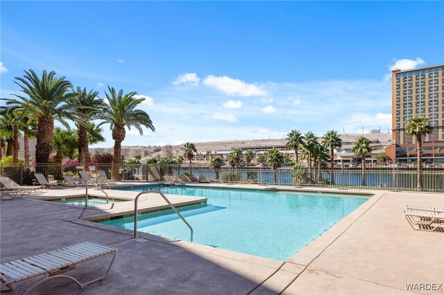 pool with a water view, fence, and a patio