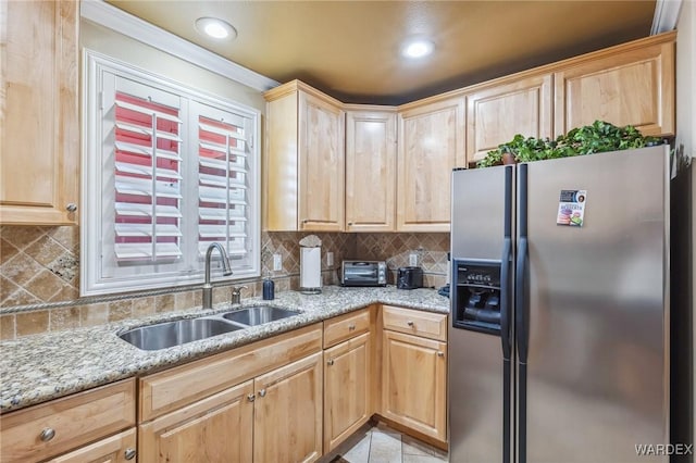 kitchen with light stone countertops, stainless steel fridge, decorative backsplash, and a sink