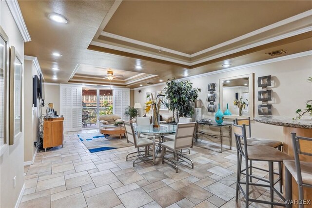 dining room with crown molding, a raised ceiling, visible vents, ceiling fan, and baseboards