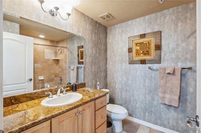 bathroom with a shower, visible vents, toilet, vanity, and tile patterned flooring