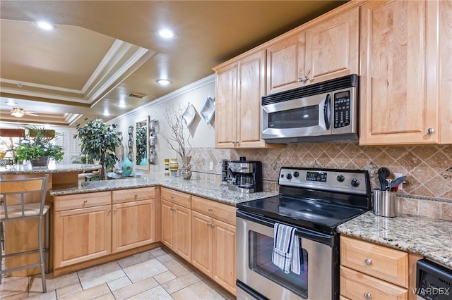 kitchen with appliances with stainless steel finishes, light stone countertops, a tray ceiling, crown molding, and light brown cabinetry