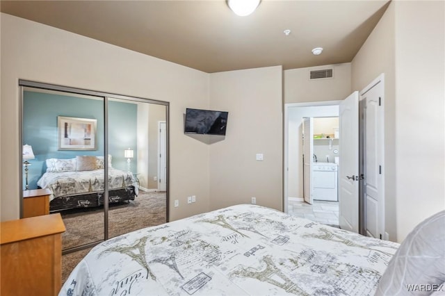 bedroom with a closet, visible vents, light colored carpet, washer / clothes dryer, and a sink