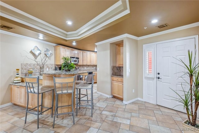 kitchen with light stone countertops, visible vents, light brown cabinets, and appliances with stainless steel finishes