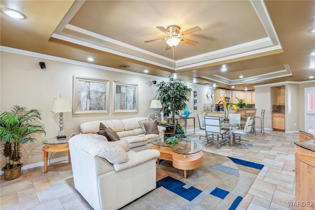 living room with a tray ceiling, crown molding, recessed lighting, ceiling fan, and baseboards