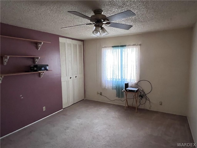 unfurnished bedroom with carpet floors, a textured ceiling, a ceiling fan, and a closet