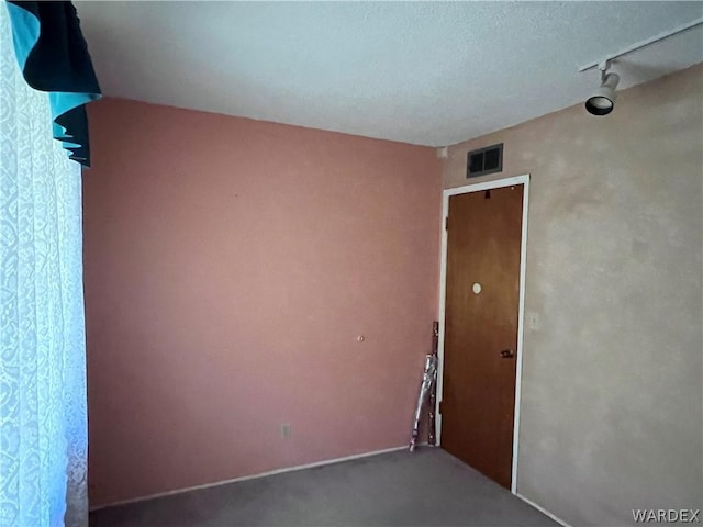 spare room featuring rail lighting and visible vents