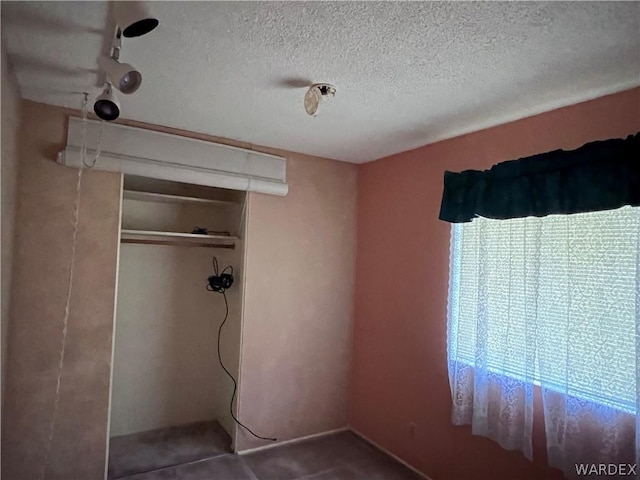 unfurnished bedroom featuring a textured ceiling and a closet