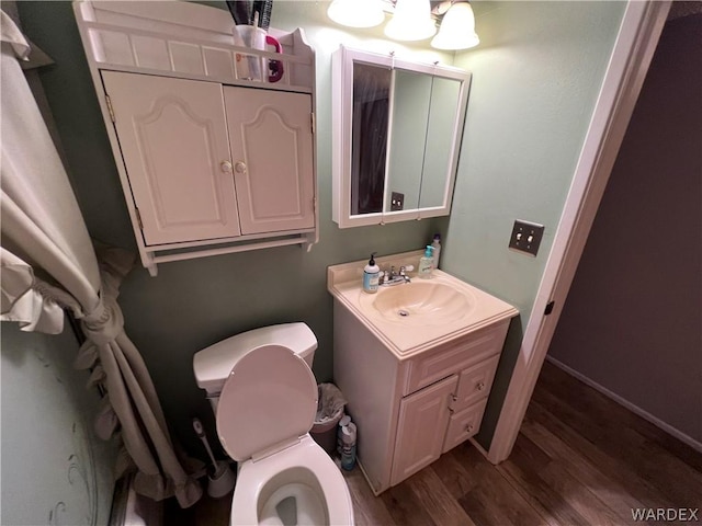 bathroom featuring toilet, wood finished floors, vanity, and baseboards