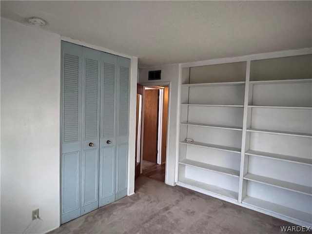 unfurnished bedroom featuring a closet, light carpet, and visible vents