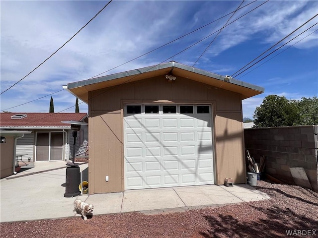 detached garage with dirt driveway and fence