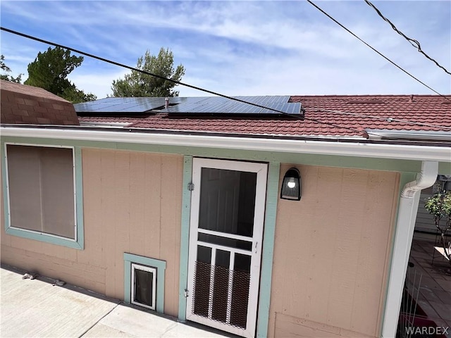 view of home's exterior featuring a tile roof and solar panels