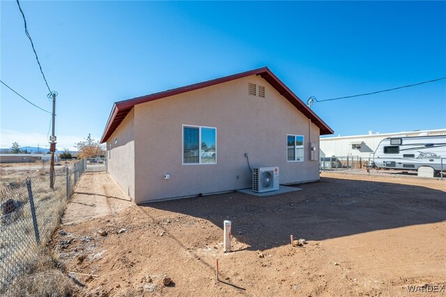 view of side of home with ac unit, fence, and stucco siding