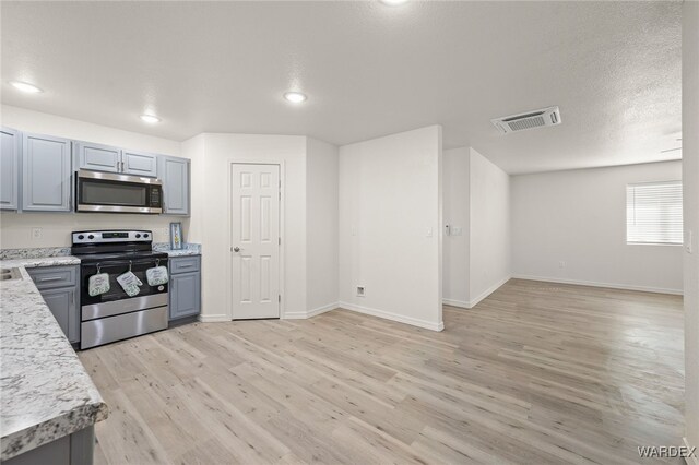 kitchen featuring baseboards, visible vents, stainless steel appliances, gray cabinetry, and light wood-type flooring