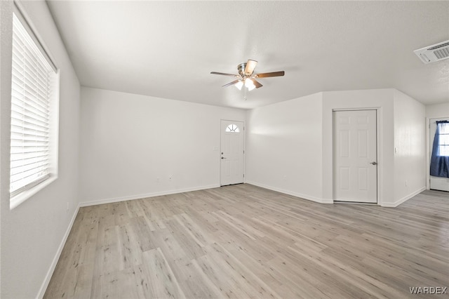 spare room featuring baseboards, a ceiling fan, visible vents, and light wood-style floors