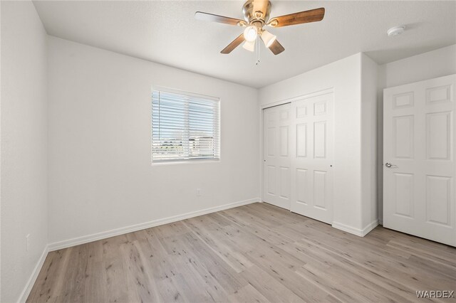 unfurnished bedroom featuring light wood-style flooring, baseboards, and a closet