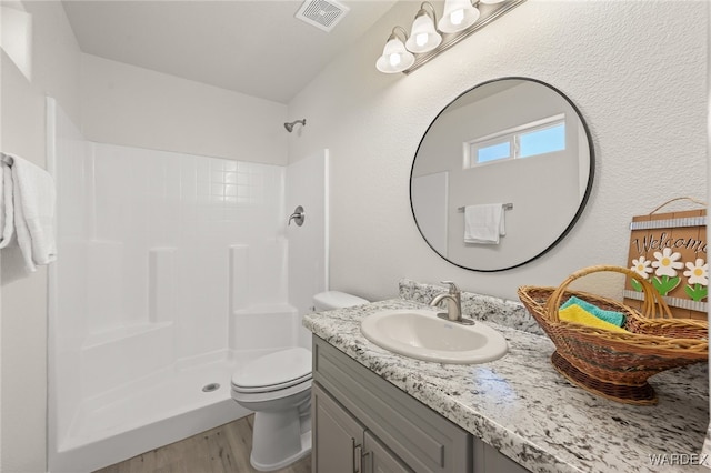 bathroom featuring a stall shower, visible vents, toilet, and wood finished floors