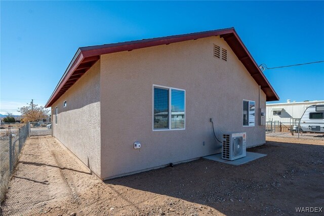 view of side of home featuring ac unit, fence, and stucco siding