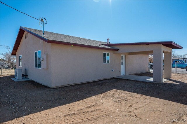 rear view of property featuring stucco siding, fence, and central AC unit