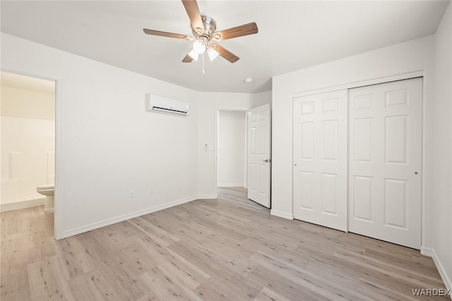 unfurnished bedroom featuring light wood-type flooring, a closet, a wall unit AC, and baseboards