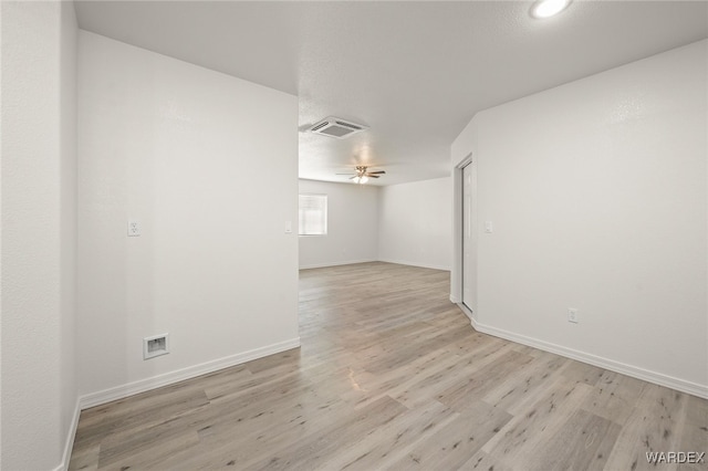 empty room featuring light wood-style flooring, visible vents, ceiling fan, and baseboards